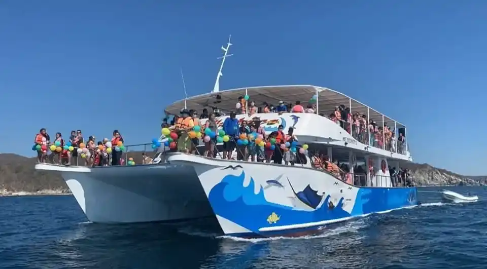 Catamaran full of visitors wearing life jackets sailing off the coast of Huatulco