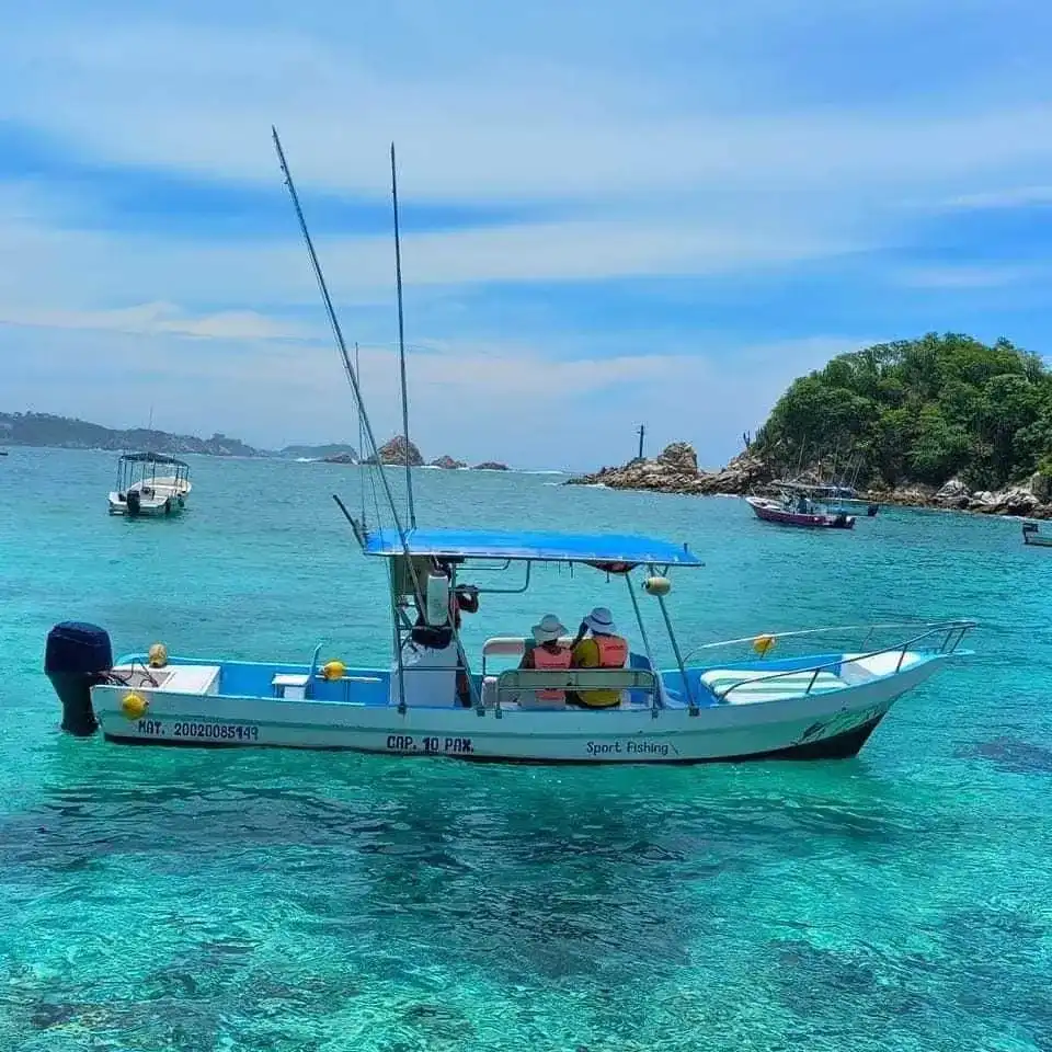 Lancha navegando en una bahía de agua turquesa rodeada de cerros verdes