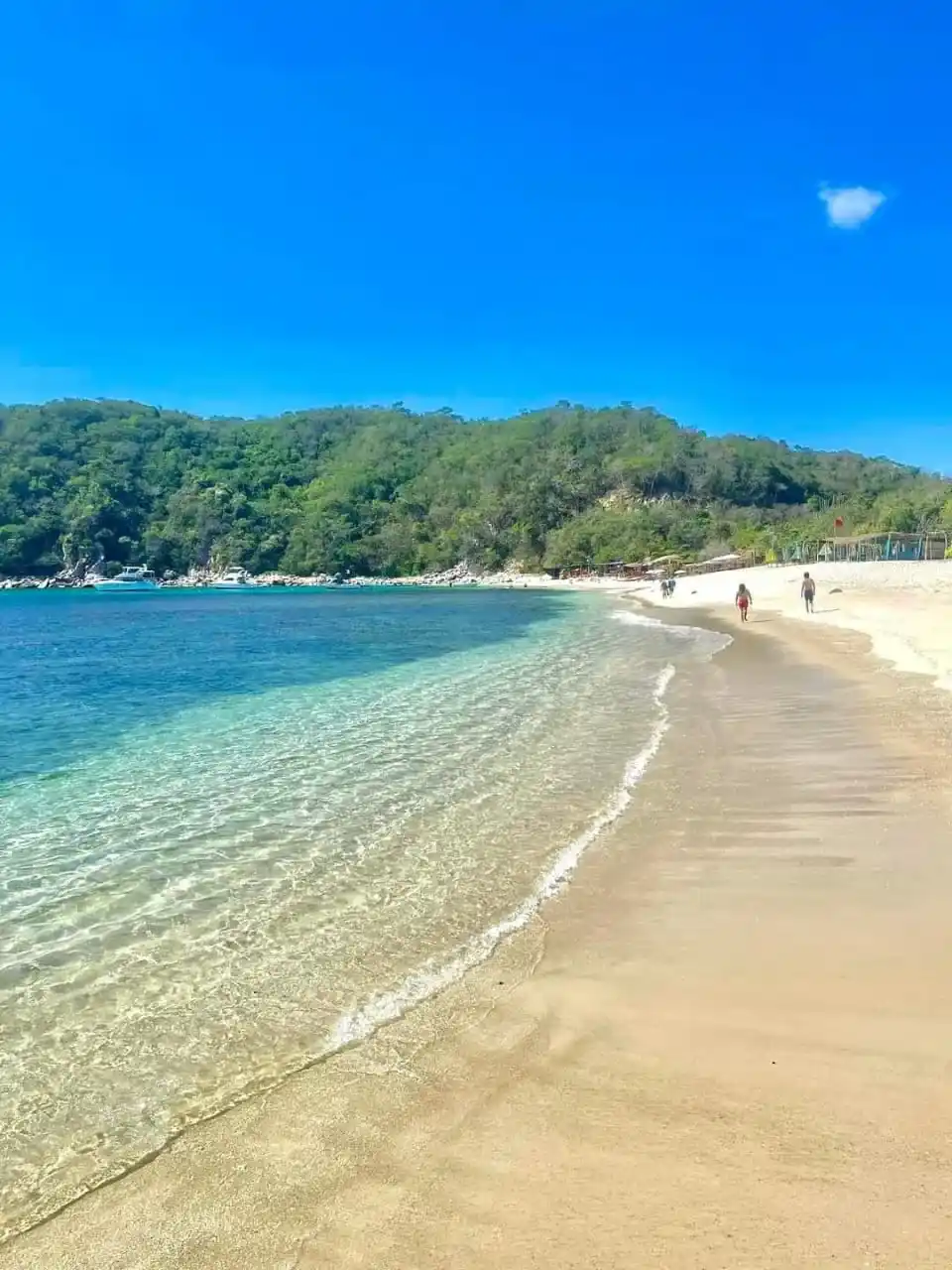 Playa de arena dorada y agua transparente en una bahía de Huatulco