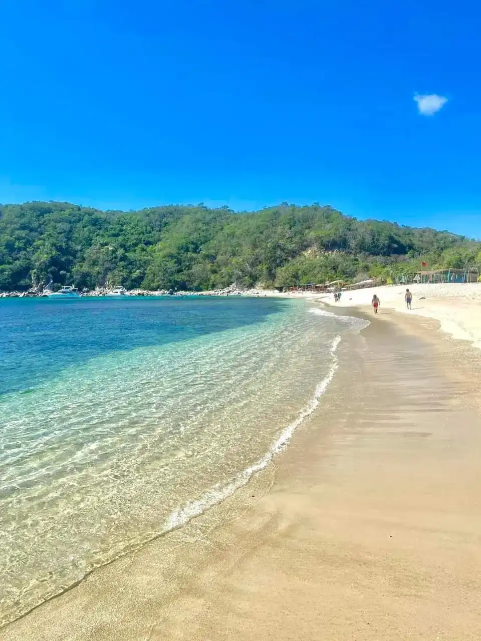 Playa de arena dorada y agua transparente en una bahía de Huatulco